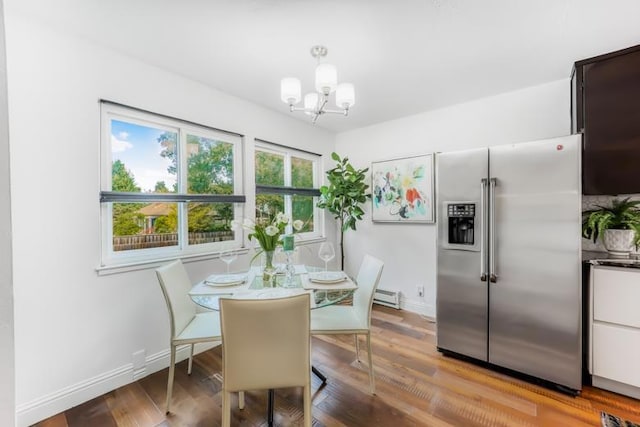 dining space with a baseboard heating unit, a chandelier, and light hardwood / wood-style flooring