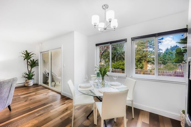 dining area featuring wood-type flooring, a chandelier, and a baseboard heating unit