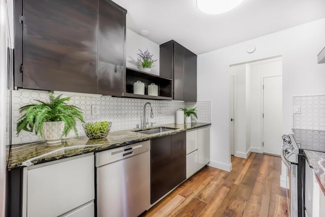 kitchen featuring appliances with stainless steel finishes, sink, dark stone countertops, and light hardwood / wood-style flooring