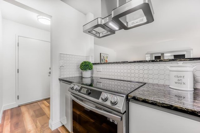 kitchen featuring white cabinetry, electric range, light hardwood / wood-style floors, decorative backsplash, and dark stone counters