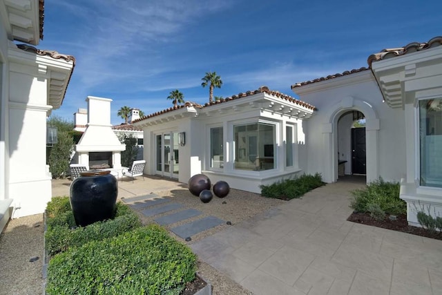 back of house featuring an outdoor fireplace and a patio