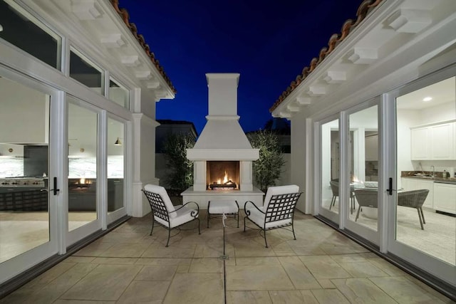 patio at twilight with an outdoor fireplace and french doors