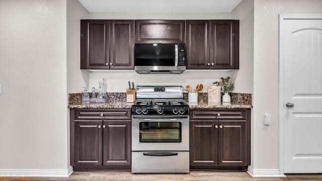 kitchen with dark stone countertops, dark brown cabinets, and appliances with stainless steel finishes