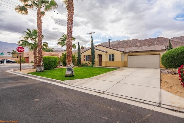 view of front of property featuring a garage, a mountain view, and a front lawn