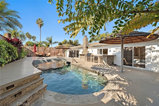 view of pool with a patio area, a grill, and an outdoor kitchen