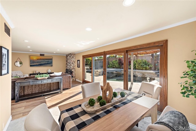 dining room with a fireplace, light hardwood / wood-style flooring, and ornamental molding