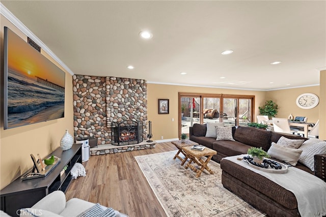 living room with light hardwood / wood-style floors, ornamental molding, and a fireplace