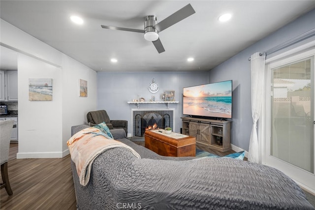 living room with ceiling fan, a brick fireplace, and hardwood / wood-style flooring