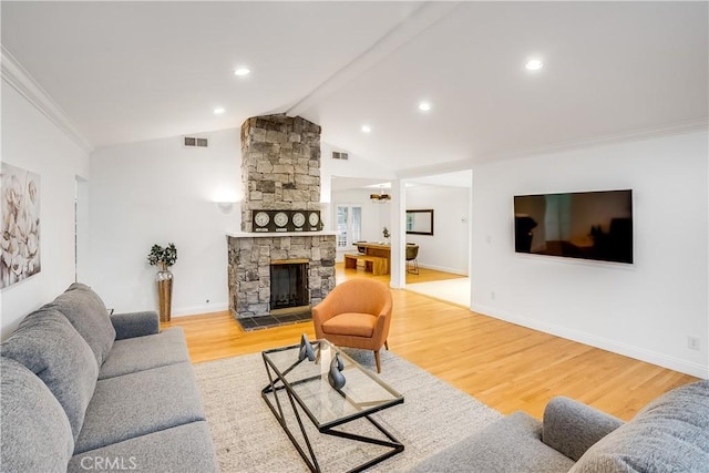 living room with hardwood / wood-style flooring, crown molding, a stone fireplace, and vaulted ceiling with beams