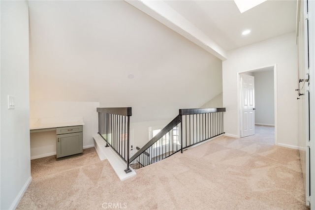 hall with vaulted ceiling with skylight and light carpet