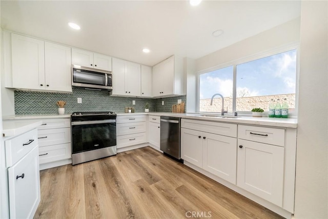 kitchen with stainless steel appliances, white cabinetry, and sink