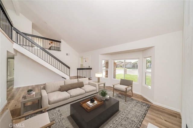 living room with high vaulted ceiling and light wood-type flooring