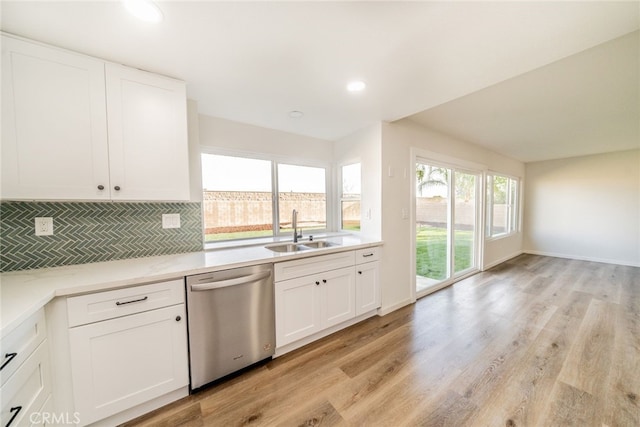 kitchen featuring backsplash, light wood-type flooring, stainless steel dishwasher, white cabinets, and sink