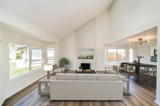 living room featuring hardwood / wood-style flooring, lofted ceiling, a chandelier, and a fireplace