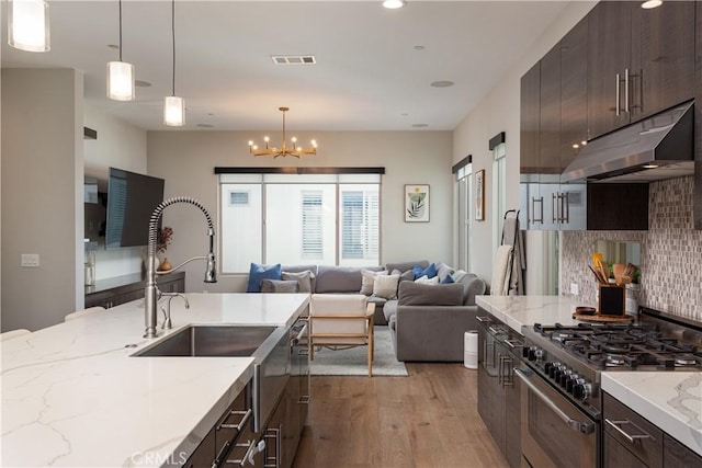 kitchen featuring decorative light fixtures, a chandelier, light stone counters, and high end stove