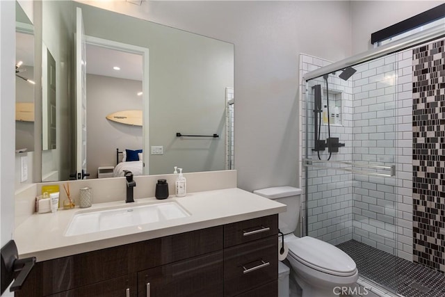 bathroom featuring toilet, vanity, and a shower with shower door