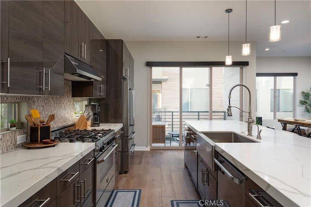 kitchen with decorative light fixtures, light stone countertops, appliances with stainless steel finishes, and light hardwood / wood-style floors