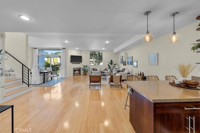 kitchen featuring pendant lighting, a kitchen bar, light stone counters, and light hardwood / wood-style flooring