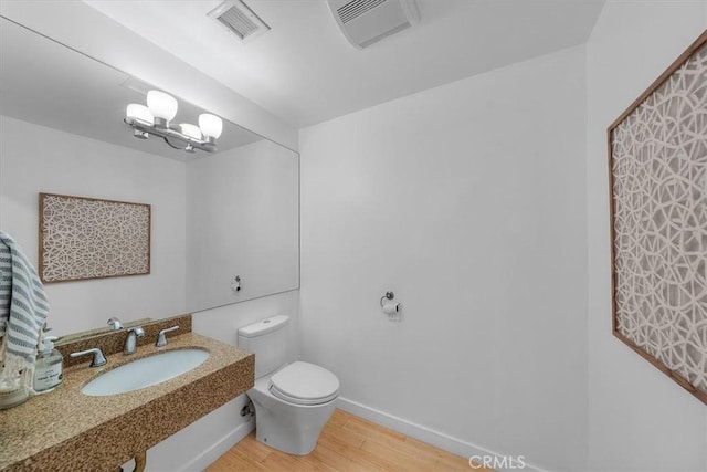 bathroom with an inviting chandelier, hardwood / wood-style flooring, toilet, and sink