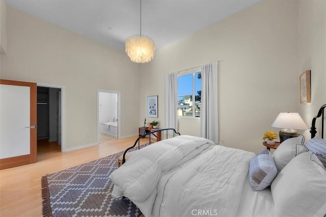 bedroom featuring connected bathroom, light hardwood / wood-style floors, and an inviting chandelier