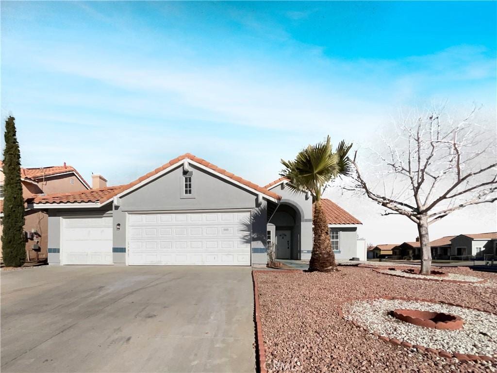 view of front facade featuring a garage, driveway, a tiled roof, and stucco siding