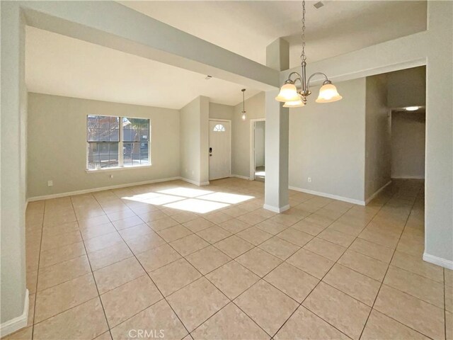 tiled empty room with lofted ceiling and a notable chandelier