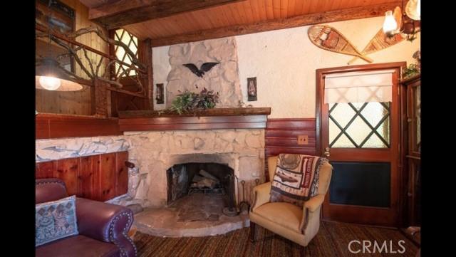 living area featuring wooden ceiling, a fireplace, and beamed ceiling