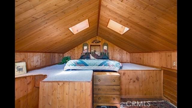 unfurnished bedroom with vaulted ceiling with skylight, wood walls, and wood ceiling