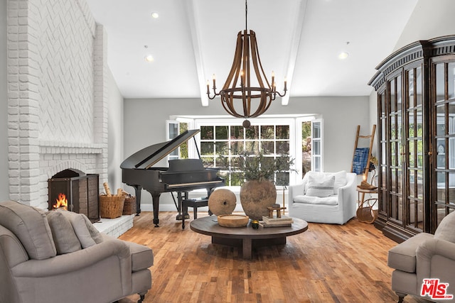 sitting room with lofted ceiling with beams, a fireplace, an inviting chandelier, and hardwood / wood-style floors