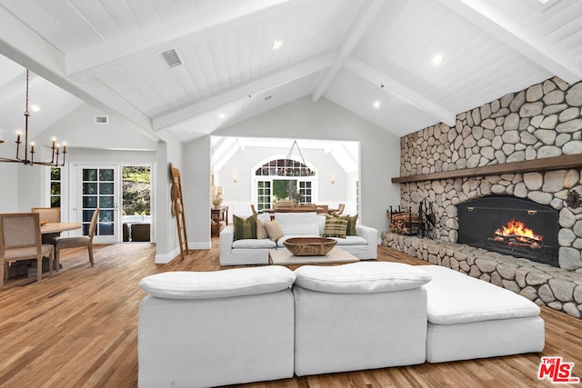 living room with beam ceiling, light wood-type flooring, a fireplace, and a chandelier