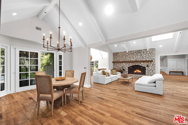 dining room with light wood-type flooring, a fireplace, high vaulted ceiling, a chandelier, and beamed ceiling