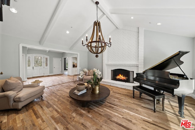 living room featuring a brick fireplace, a chandelier, wood-type flooring, and lofted ceiling with beams