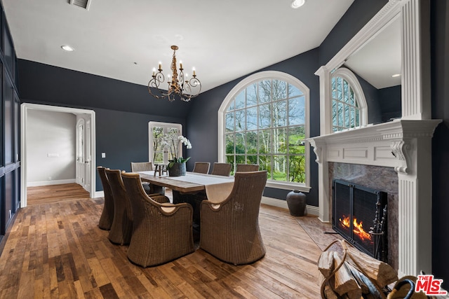 dining space featuring a chandelier, light hardwood / wood-style floors, and a fireplace