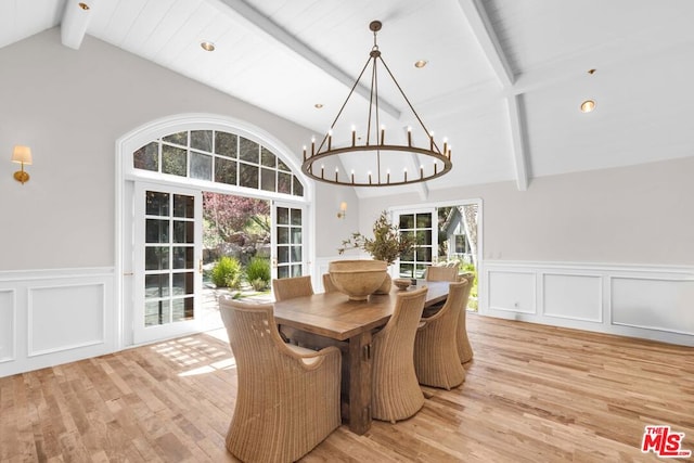 dining room featuring light hardwood / wood-style floors, lofted ceiling with beams, and a notable chandelier