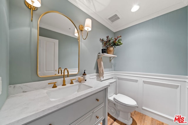 bathroom with toilet, vanity, wood-type flooring, and ornamental molding