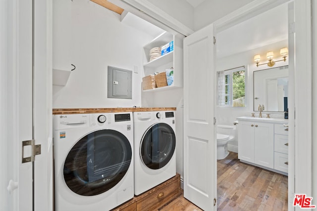 laundry room with washer and dryer, sink, light hardwood / wood-style flooring, and electric panel