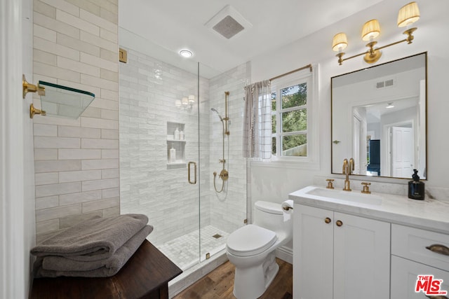 bathroom featuring vanity, toilet, wood-type flooring, and walk in shower