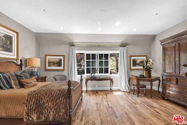 bedroom with light wood-type flooring and vaulted ceiling