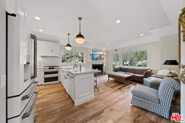 kitchen featuring backsplash, decorative light fixtures, white appliances, white cabinets, and light stone counters