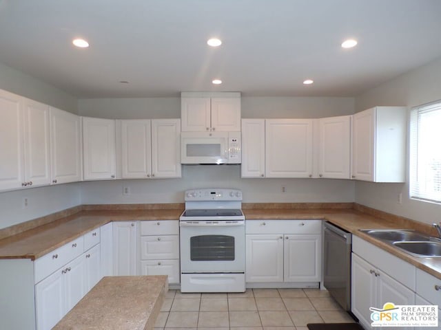 kitchen featuring light tile patterned floors, sink, white appliances, and white cabinetry