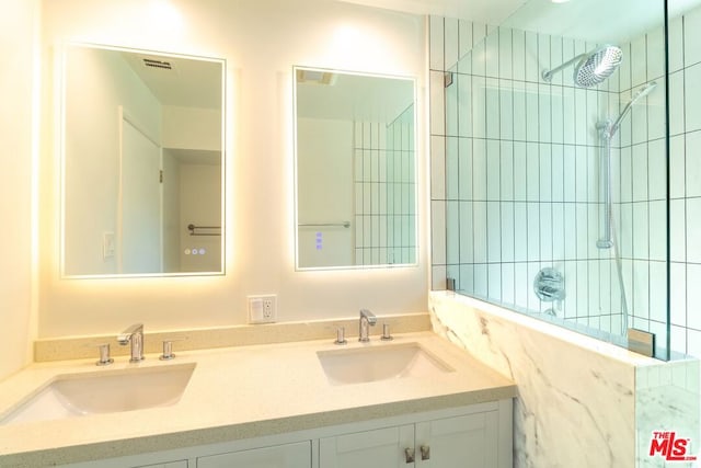 bathroom with a tile shower and vanity