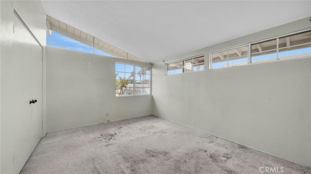 carpeted empty room featuring lofted ceiling