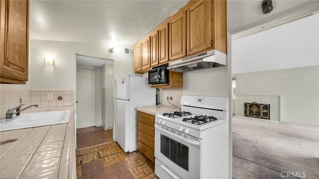 kitchen with backsplash, tile countertops, sink, white appliances, and dark parquet floors