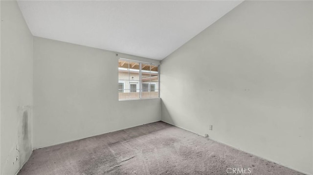 carpeted spare room featuring vaulted ceiling