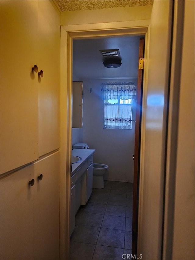 bathroom featuring toilet, vanity, and tile patterned flooring