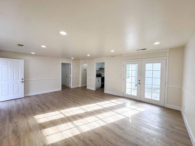 unfurnished living room with light wood-type flooring and french doors