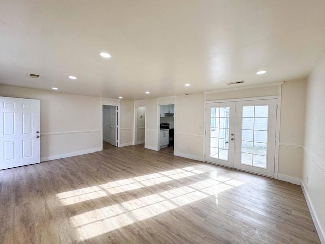 unfurnished living room with light hardwood / wood-style flooring and french doors