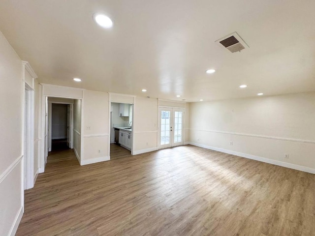 unfurnished living room with light wood-type flooring and french doors