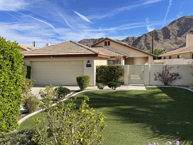 ranch-style home featuring a front yard, a mountain view, and a garage