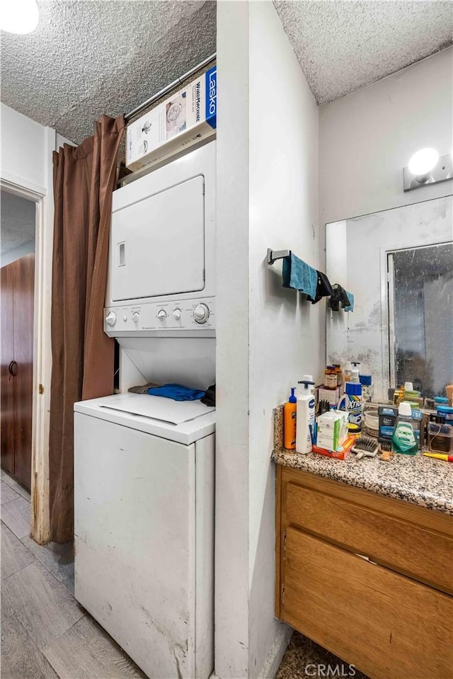 washroom featuring stacked washer / dryer and a textured ceiling